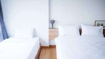 Una habitación de hotel con dos camas individuales, una mesita de noche de madera con un jarrón de flores y un cuadro en la pared.