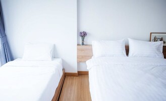 Una habitación de hotel con dos camas individuales, una mesita de noche de madera con un jarrón de flores y un cuadro en la pared.