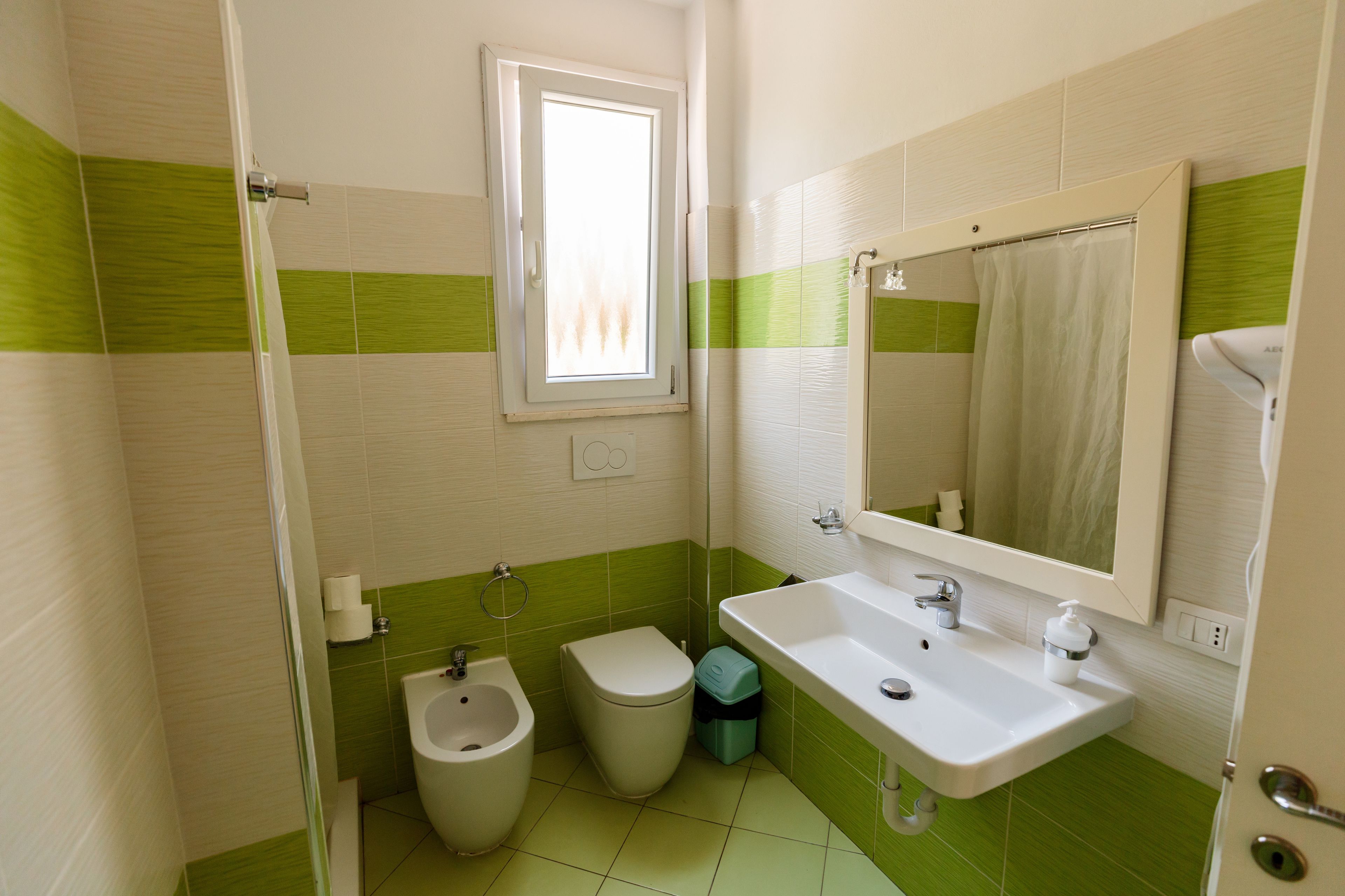 A bathroom with a bidet, toilet, sink, and a window.