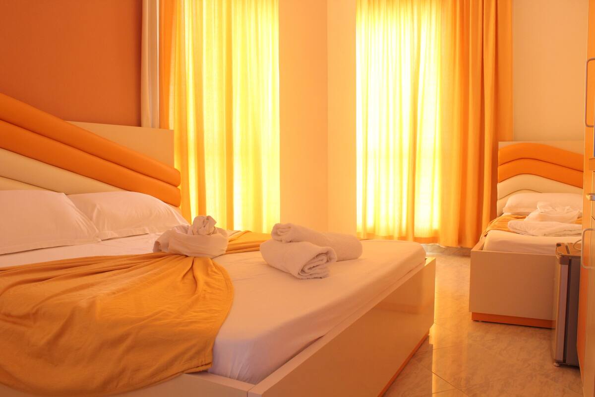 A hotel room with a bed, a bedside table, and a wardrobe.