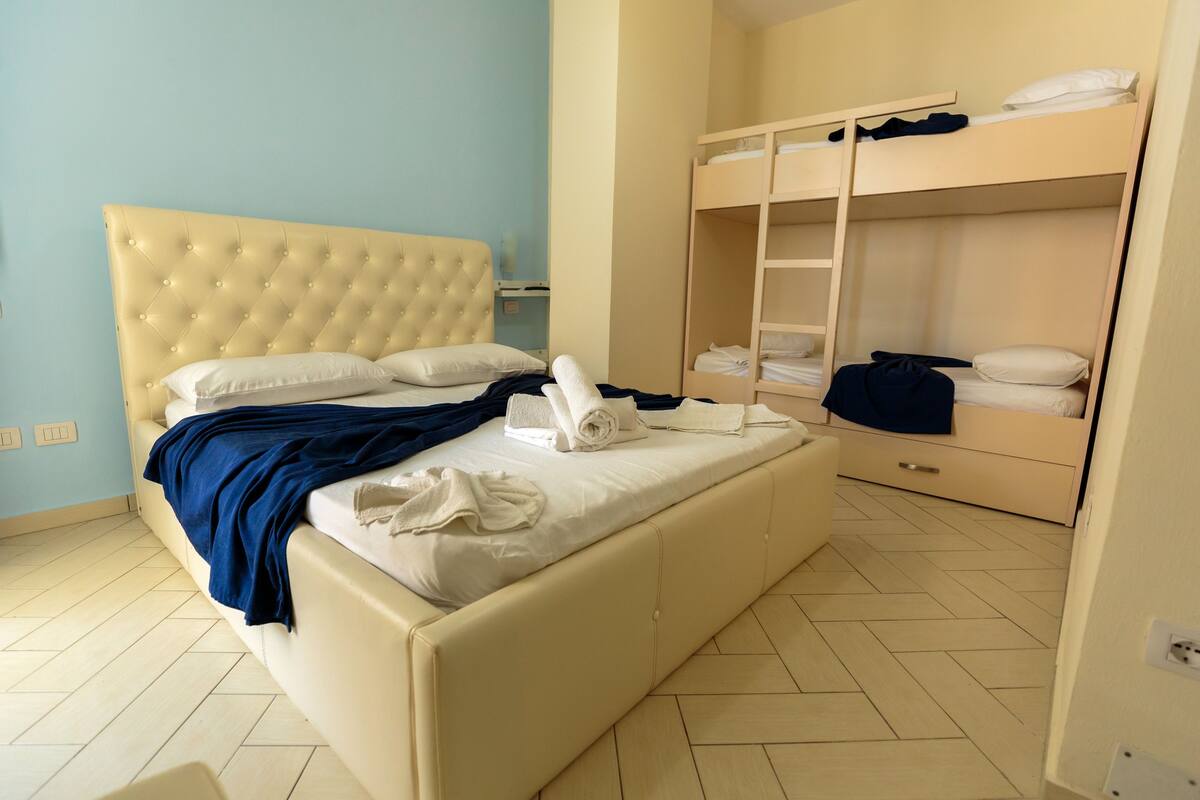 A room with a large bed, a bunk bed, and a wardrobe.