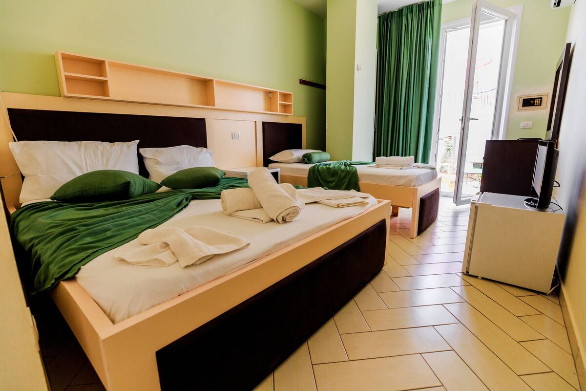 A hotel room with two beds, a desk, and a TV.