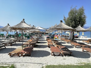 Na praia, espreguiçadeiras, guarda-sóis 