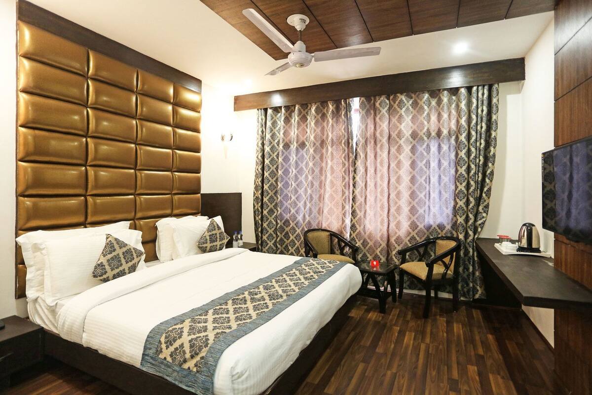Una habitación de hotel con una cama grande, un escritorio con silla, un televisor y un ventilador de techo.