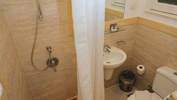 A bathroom with a shower, sink, toilet, and a mirror.