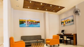 A modern lobby with a sofa, two armchairs, a desk with a computer, and two paintings on the walls. - Hapi Hotel (Aswan)