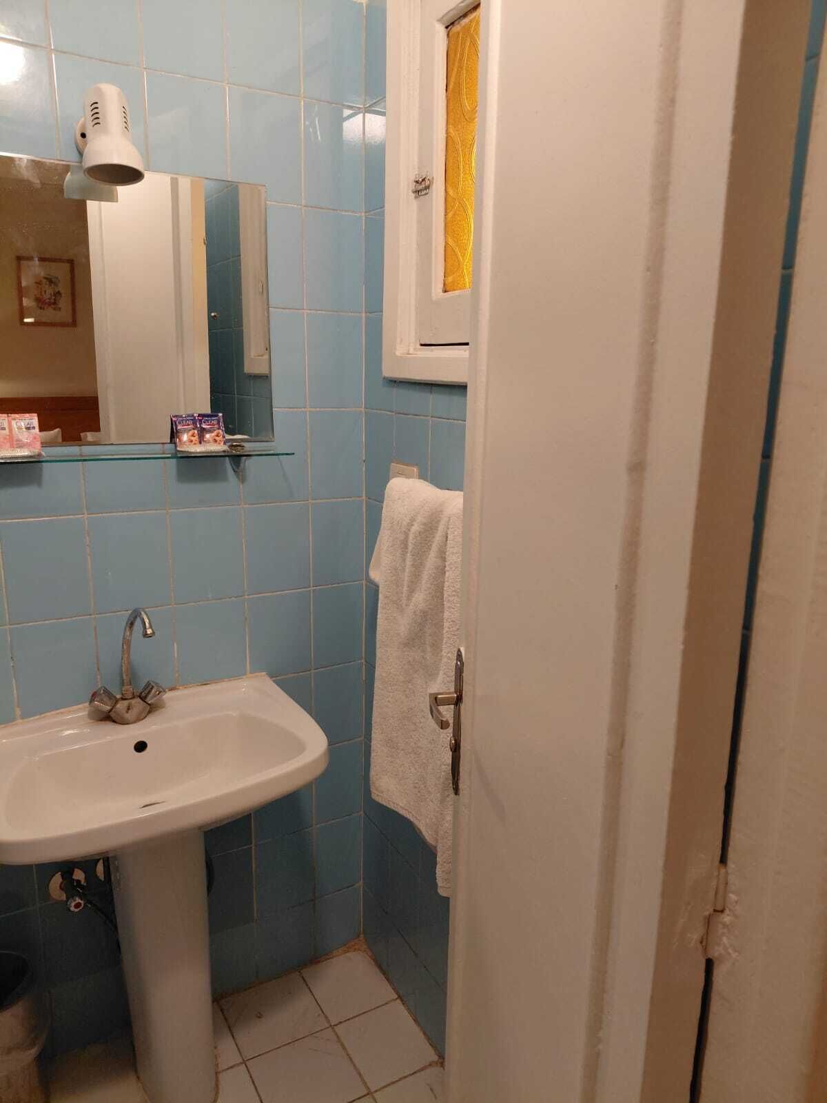Een badkamer met een wastafel, spiegel en handdoekrek.