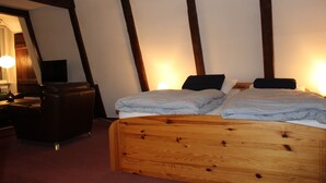 Un dormitorio con cabecera de madera, cama con ropa de cama a rayas, una silla y un escritorio con lámpara.