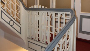 Una escalera con barandas blancas ornamentadas y una alfombra roja.