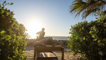 Relax on a serene beach with a bench overlooking the ocean, surrounded by lush greenery.