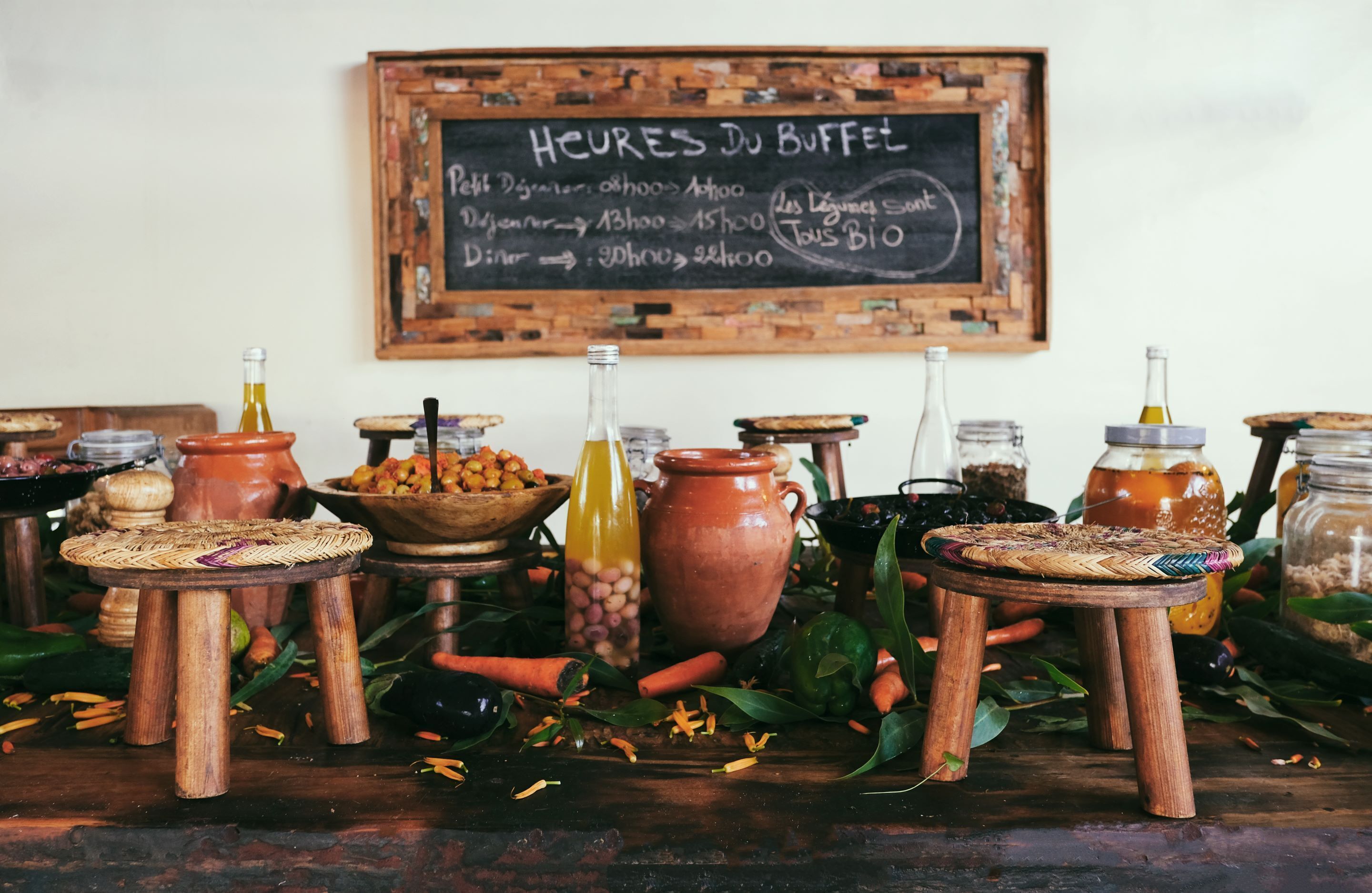 A rustic buffet setup with wooden stools, jars, and a chalkboard menu.