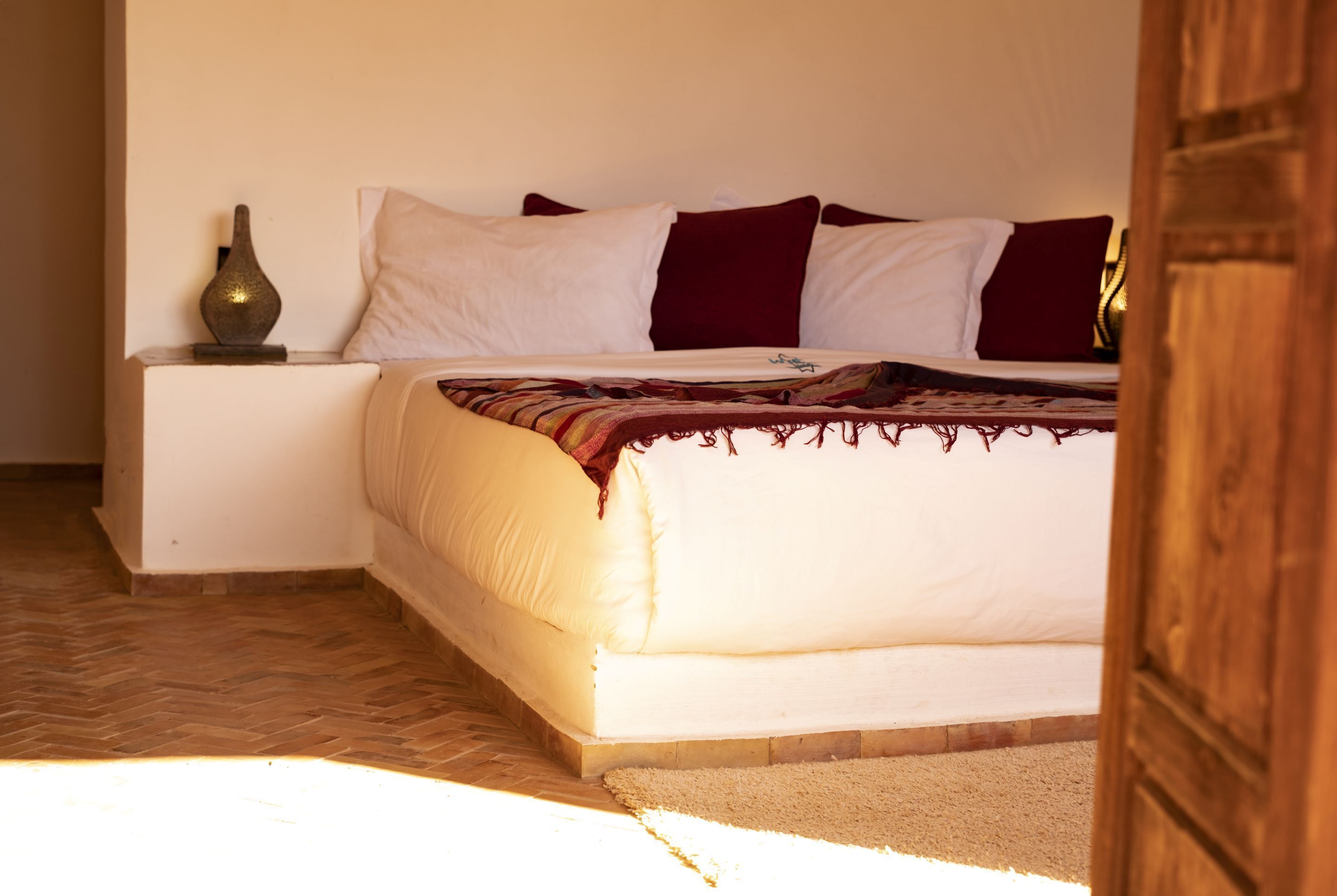 A bedroom with a bed, pillows, a bedside table, and a nightstand.