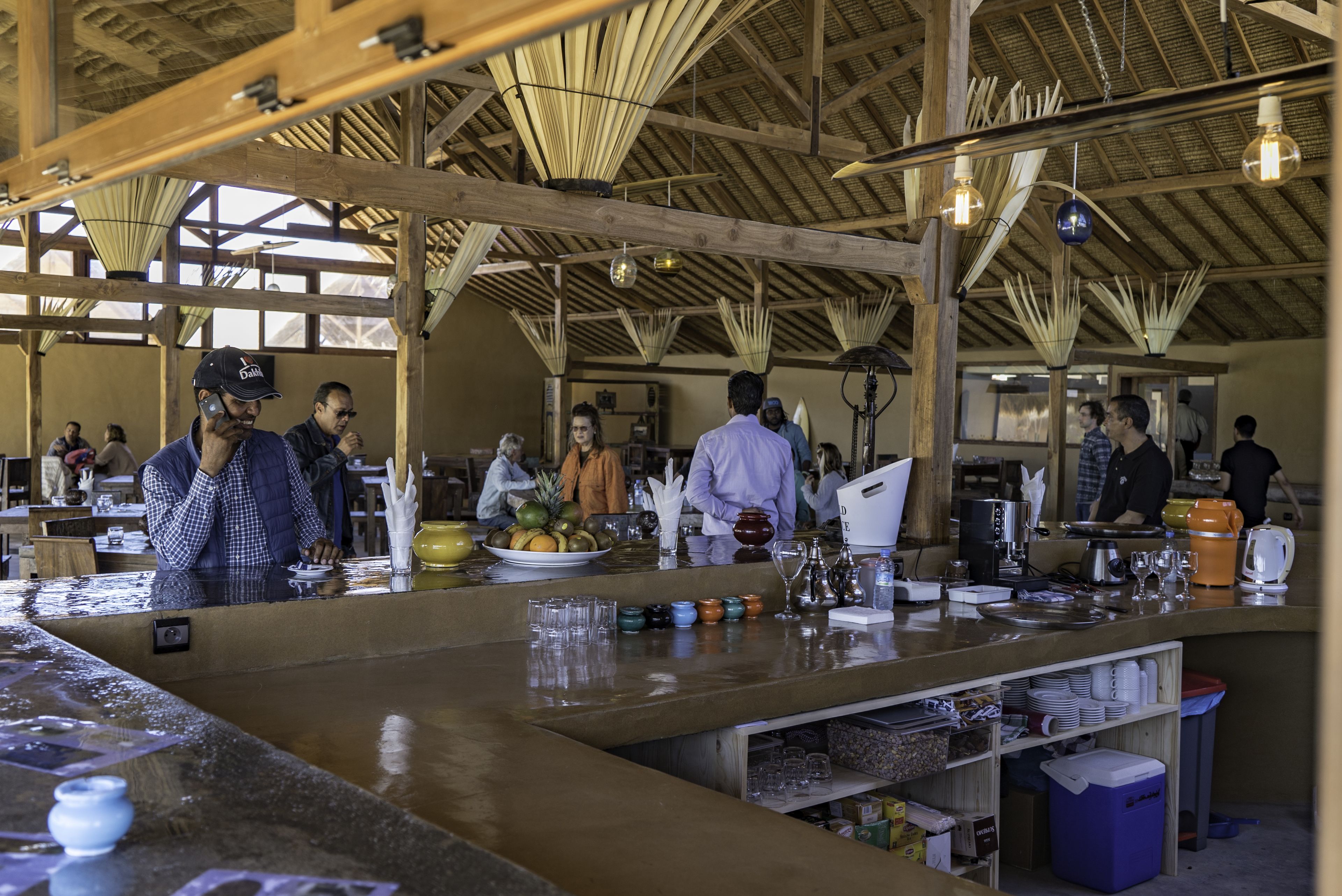 A spacious bar area with wooden beams, a long counter, and various bar tools and glasses.