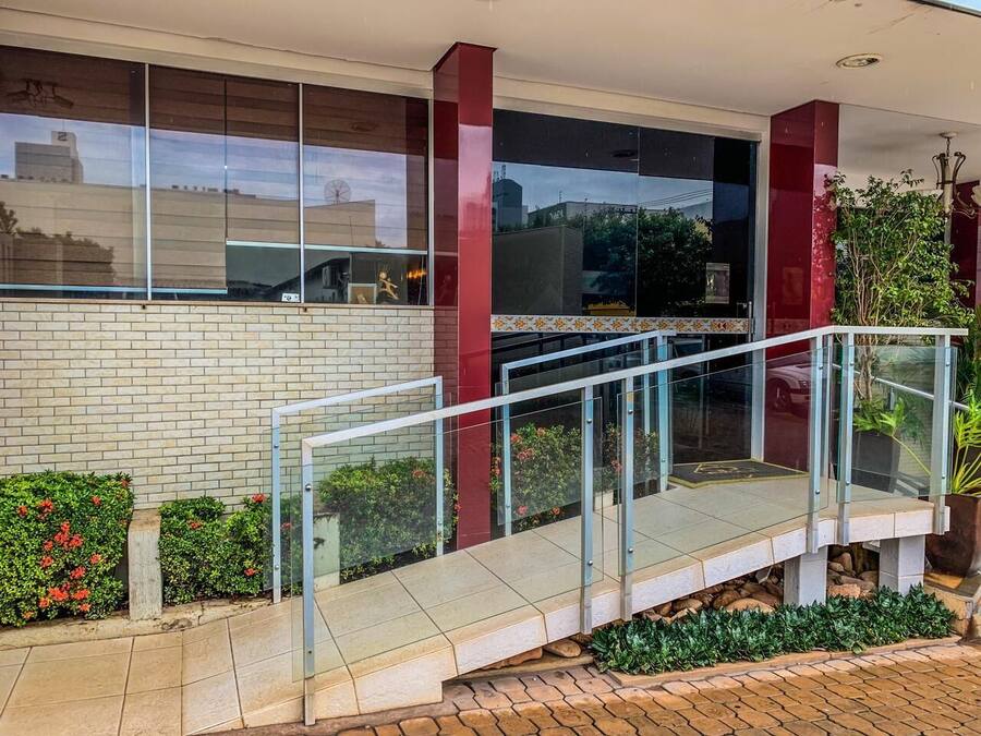 A modern building with a glass entrance, a brick facade, and a small outdoor seating area with plants.