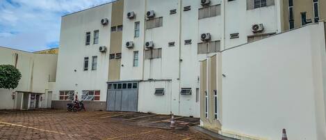 Un edificio con varias unidades de aire acondicionado, un patio empedrado y una motocicleta estacionada.