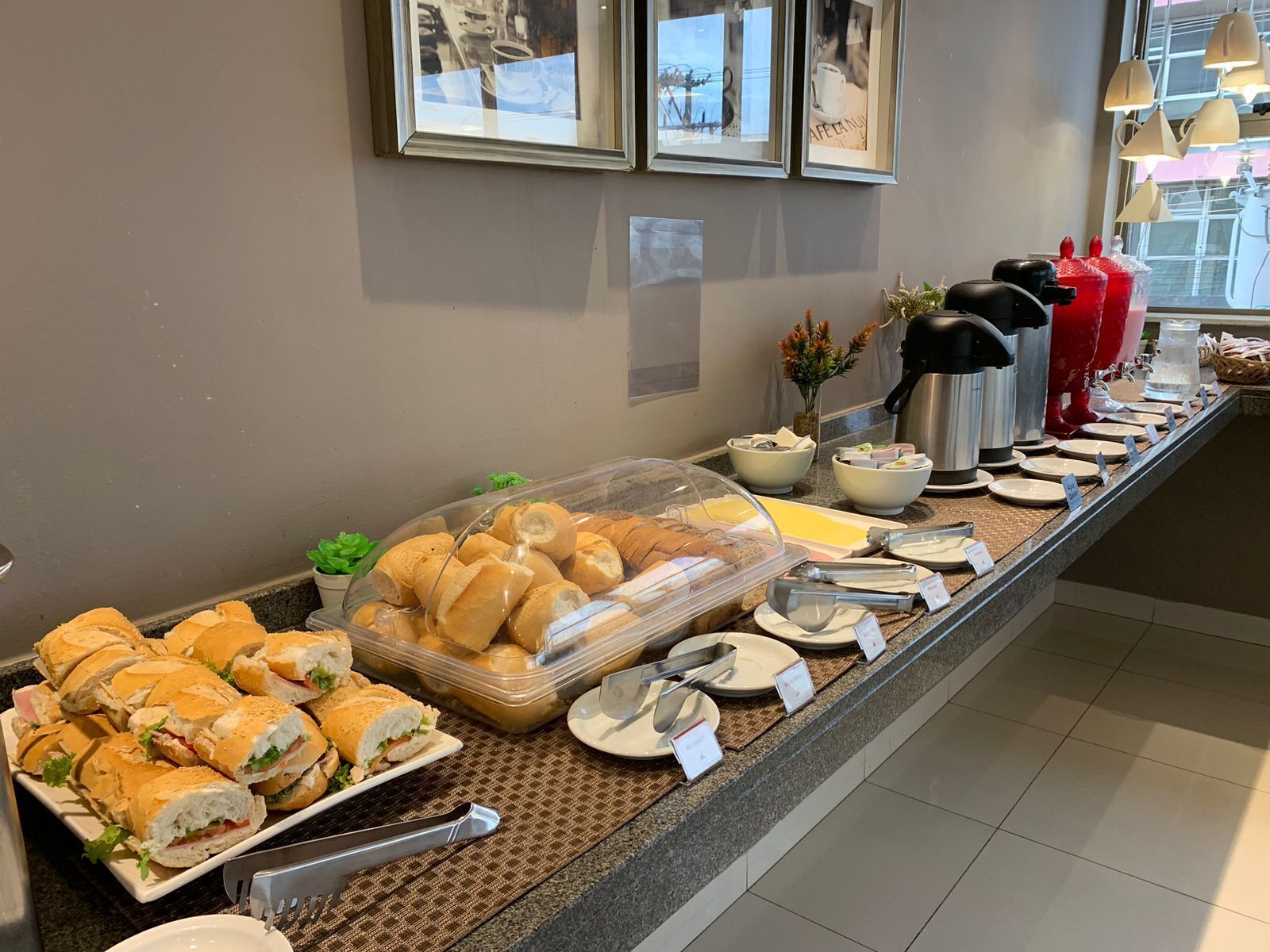 A buffet setup with sandwiches, bowls, and coffee makers.