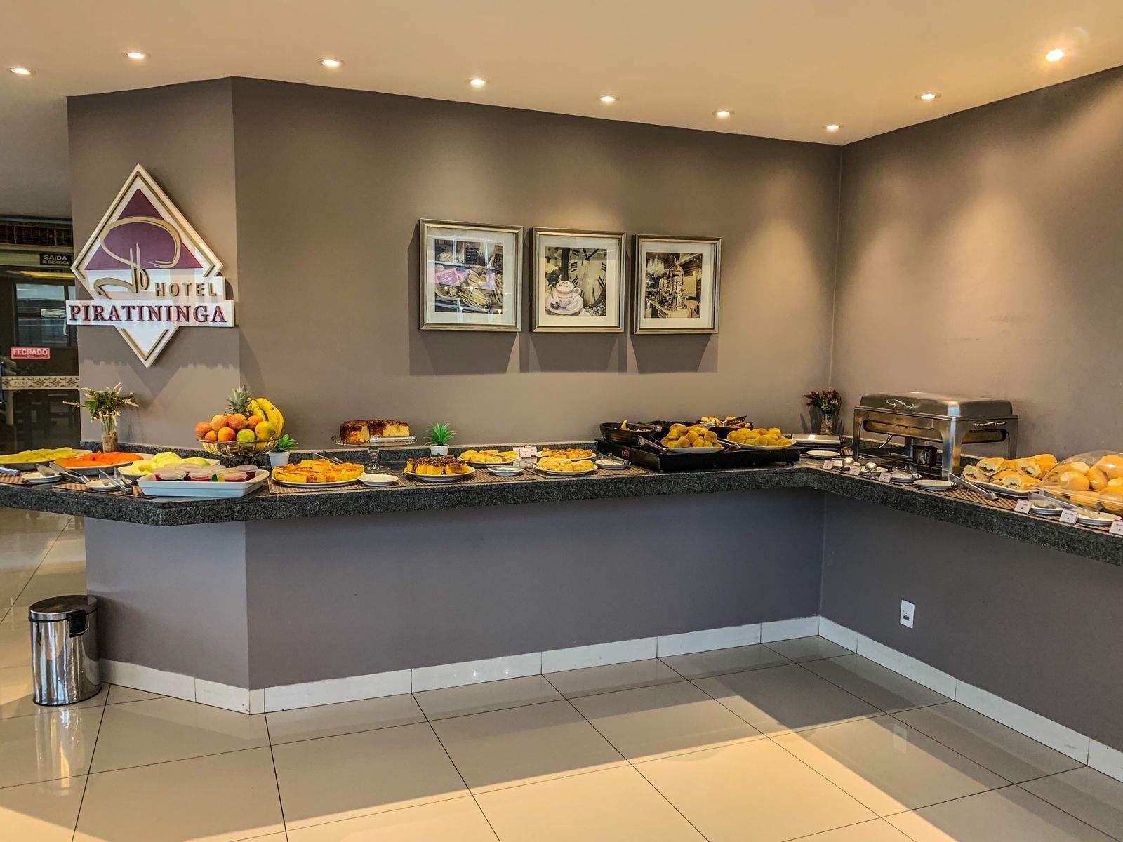 Un buffet d’hôtel proposant une variété de plats, des tableaux encadrés accrochés au mur et une poubelle.