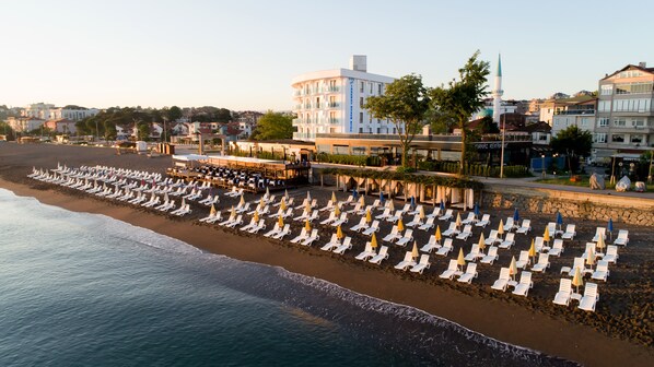 A beachside hotel with rows of sun loungers and umbrellas, a pool area, and a view of the sea. - Turkuaz Beach Hotel (Akcakoca)