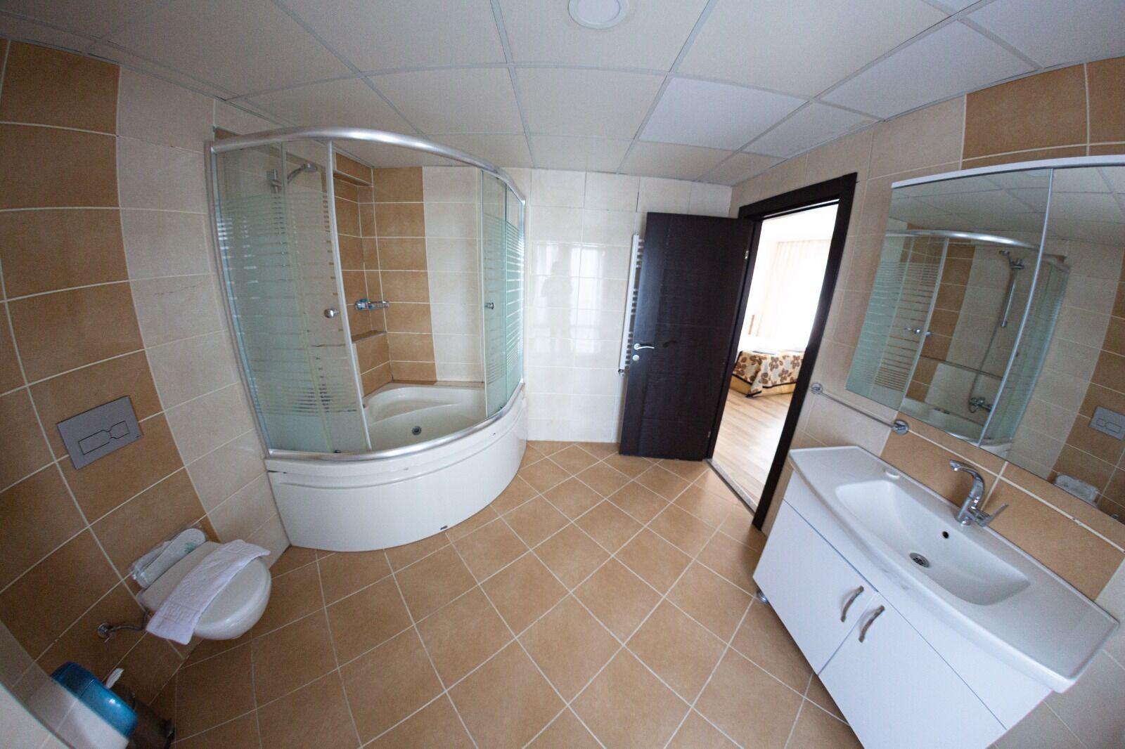 Une salle de bain avec un jacuzzi entouré de parois en verre, un lavabo blanc et un grand miroir.