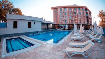 Alberca al aire libre, sombrillas en la alberca y camastros