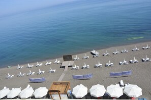 A beach with rows of sun loungers and umbrellas, a wooden deck, and a view of the sea. - Turkuaz Beach Hotel (Akcakoca)
