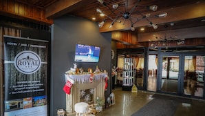 A hotel lobby with a fireplace, a television mounted on the wall, and a reception desk. - Royal Boutique Hotel Poiana Brasov (Brasov)