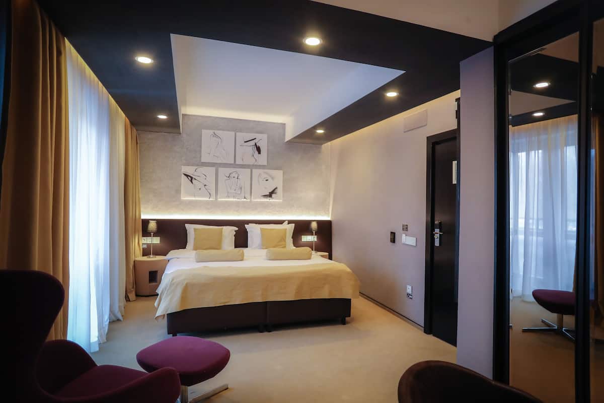 A modern hotel room with a large bed, bedside tables, a desk, and a chair.