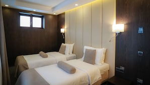 A hotel room with two beds, a window, wall-mounted lights, and a wooden panel wall. - Royal Boutique Hotel Poiana Brasov (Brasov)