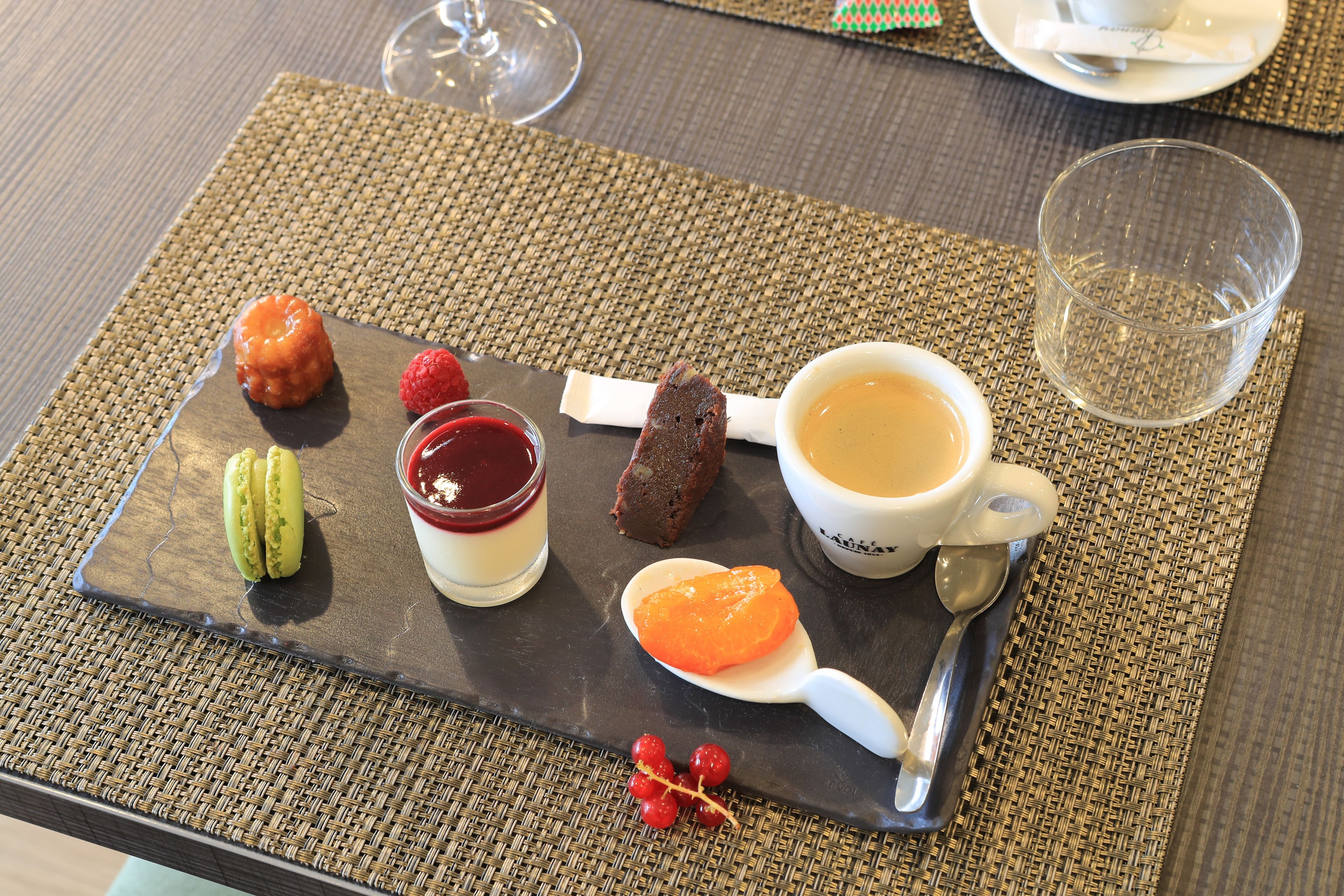 A dessert tray with various sweets and a cup of coffee on a table.