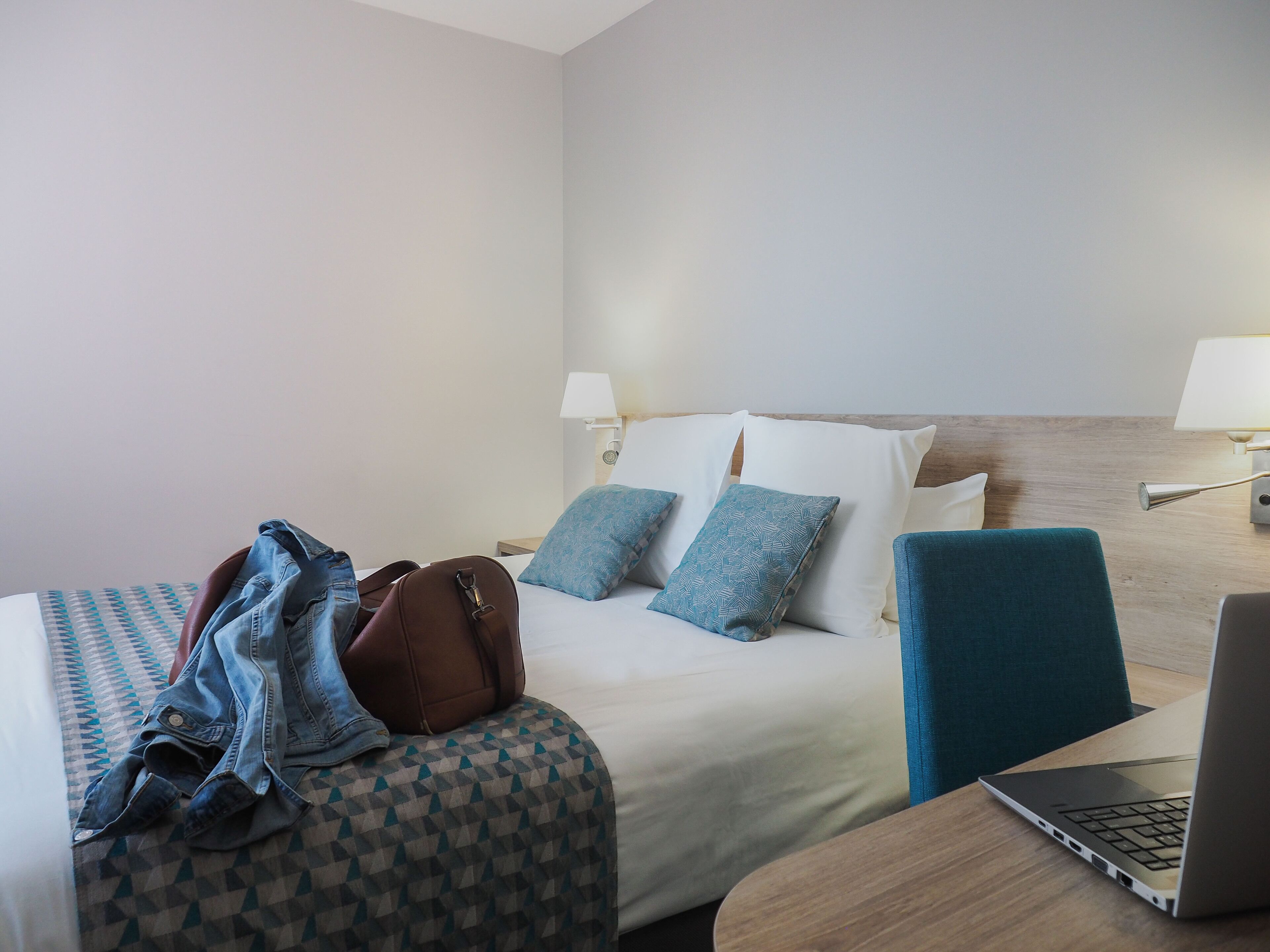 A hotel room with two beds, a desk with a laptop, and a chair.
