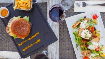 Un repas composé d’un hamburger, de frites et d’une salade, servi sur une table.