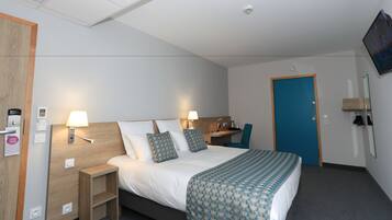 A hotel room with a bed, bedside tables, a desk, a chair, a TV, and a door.