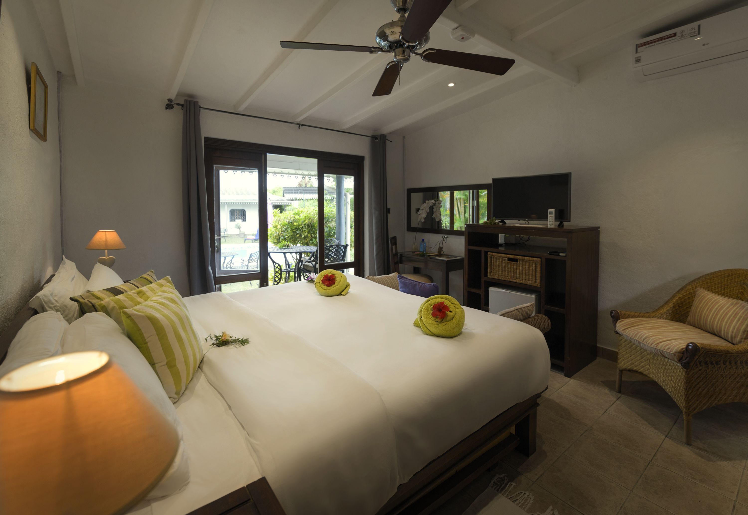 A hotel room with a bed, a television, a chair, and a ceiling fan.