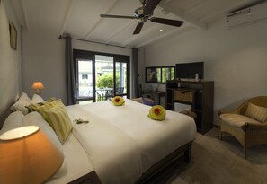 A hotel room with a bed, a television, a chair, and a ceiling fan. - Auberge Chez Plume (Mahé Island)