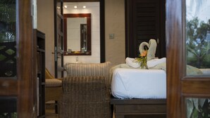A bedroom with a bed, a ceiling fan, a wooden door, and a view of the outdoors. - Auberge Chez Plume (Mahé Island)