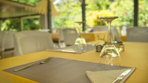 A dining table set with a fork, knife, and napkin, with a clear glass vase and a candle holder on the table. - Auberge Chez Plume (Mahé Island)