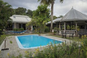 Relax by the serene pool surrounded by lush greenery and a gazebo.