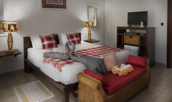 A neatly arranged bedroom with a bed, a sofa, a television, and a small table.