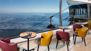 A high-altitude restaurant with panoramic views, modern seating, and a glass-walled terrace. - Hotel Pilatus Kulm (Kriens)