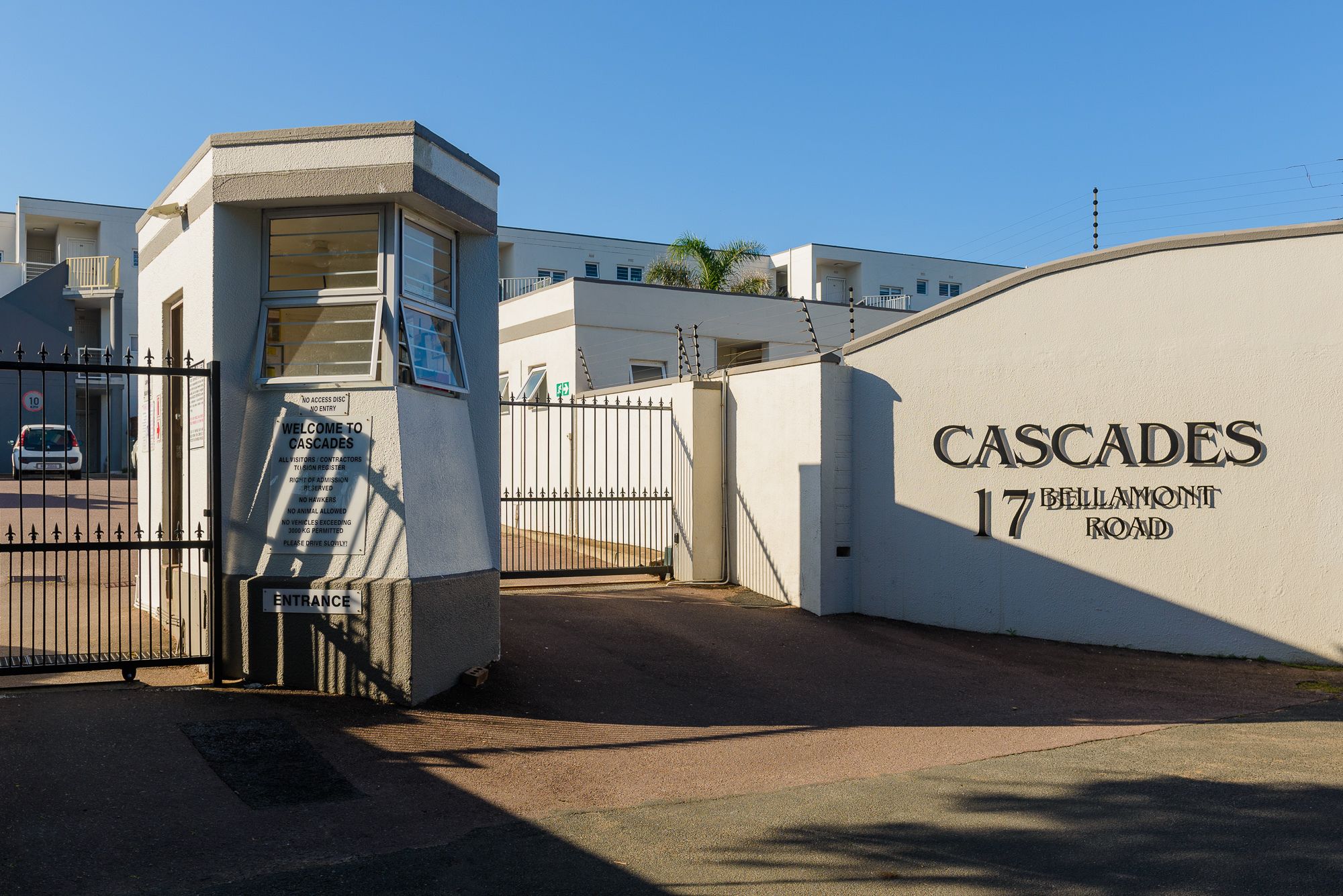 A gated entrance to Cascades at 17 Bellamont Road with a clear sky and a white building facade.