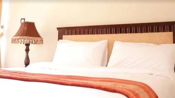 A neatly made bed with white linens and a brown headboard.