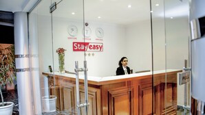 A reception desk with a glass partition, clocks displaying different time zones, and a 'Stay easy' sign. - Stay Easy (Addis Ababa)
