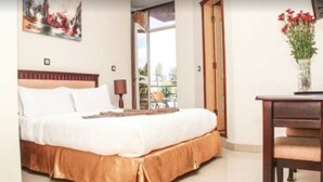 A bedroom with a bed, a desk, and a chair. There is a window with a view of the outdoors. - Stay Easy (Addis Ababa)