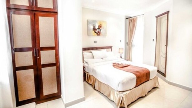 A hotel room with a bed, a wardrobe, and a painting on the wall. - Stay Easy (Addis Ababa)