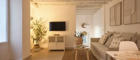 Una sala de estar moderna con un sofá, una mesa de centro, un televisor y una planta en maceta.