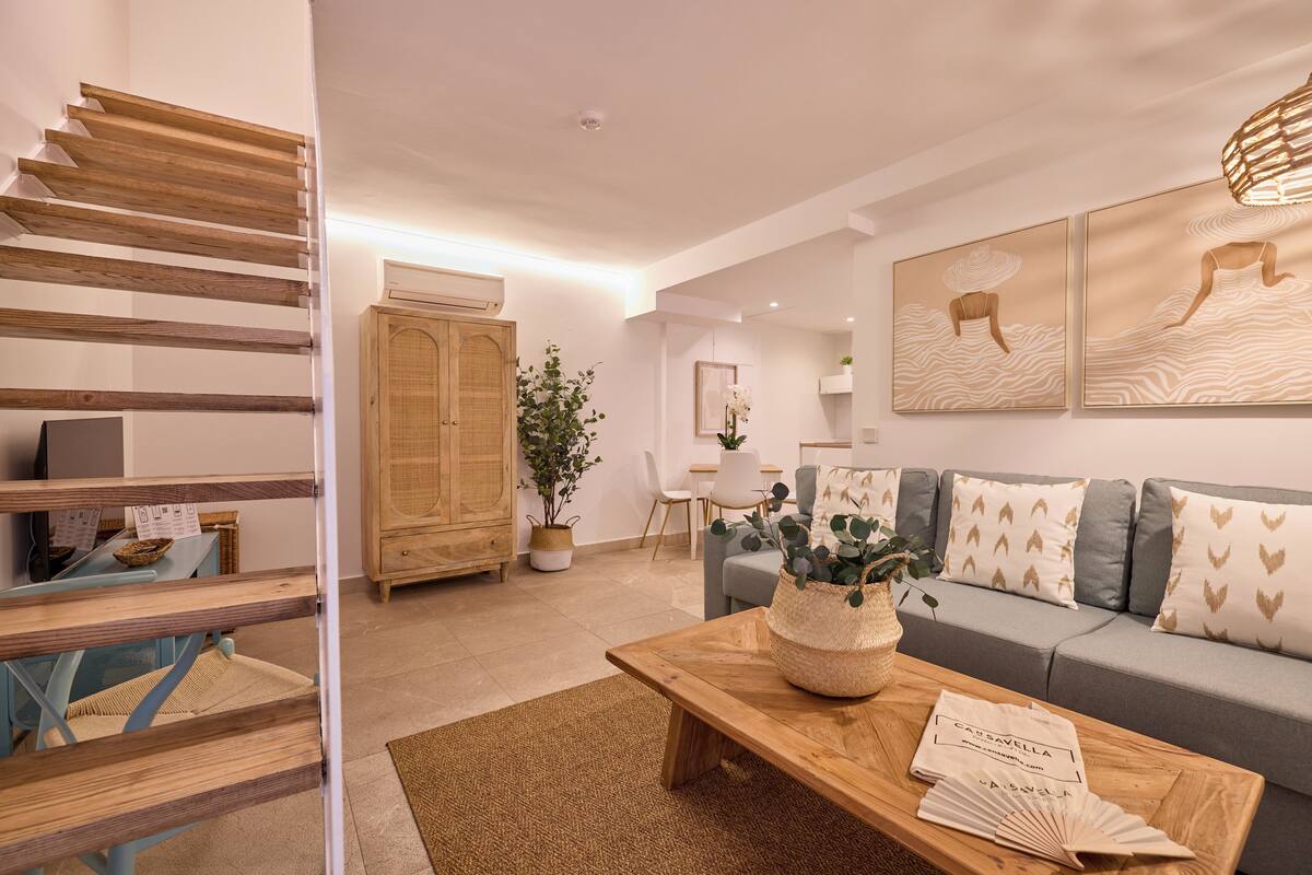Una sala de estar moderna con una escalera de madera, un sofá gris y una mesa de centro con una cesta trenzada.