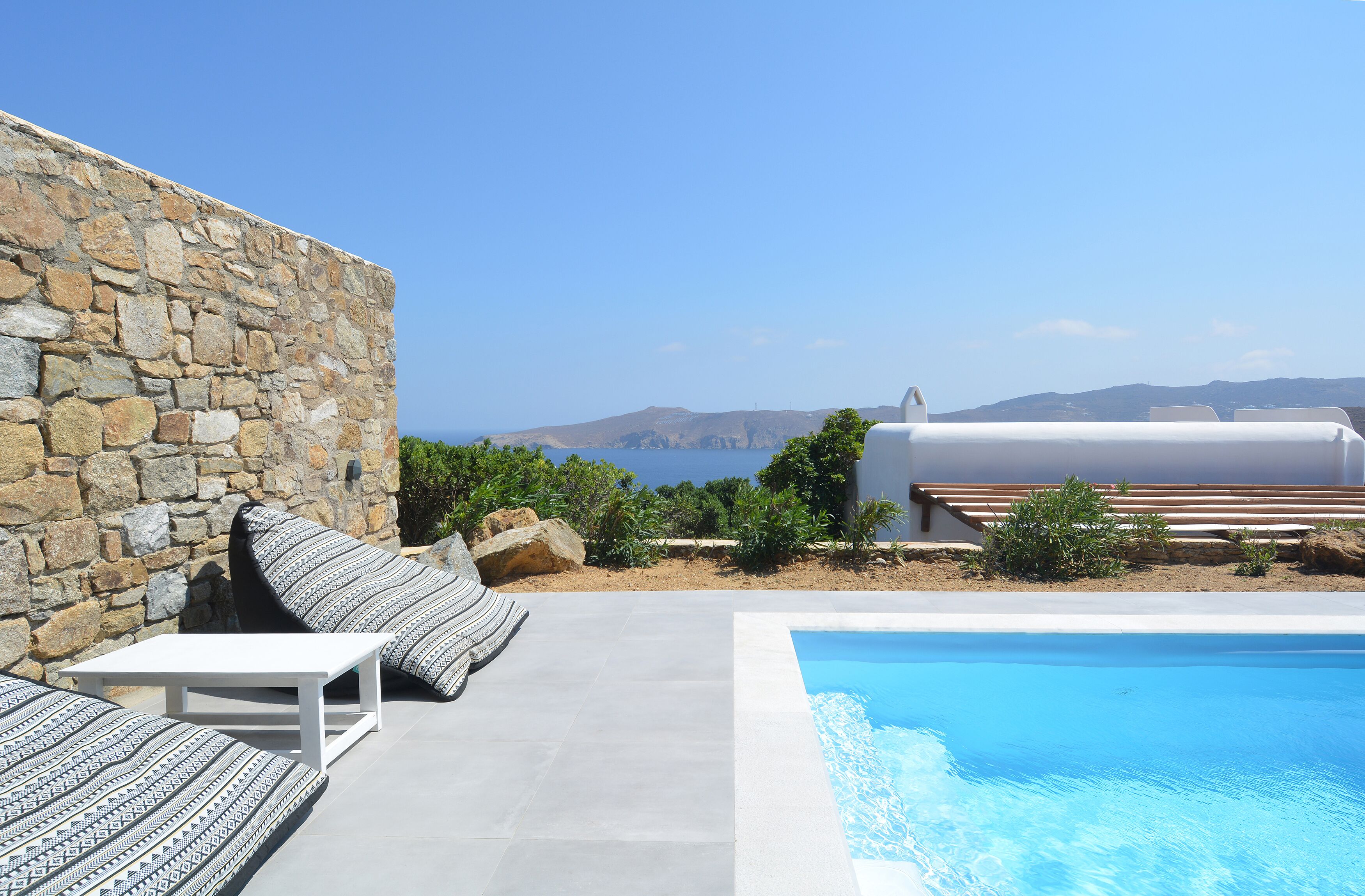 A stone wall, a pool, and a view of the sea.