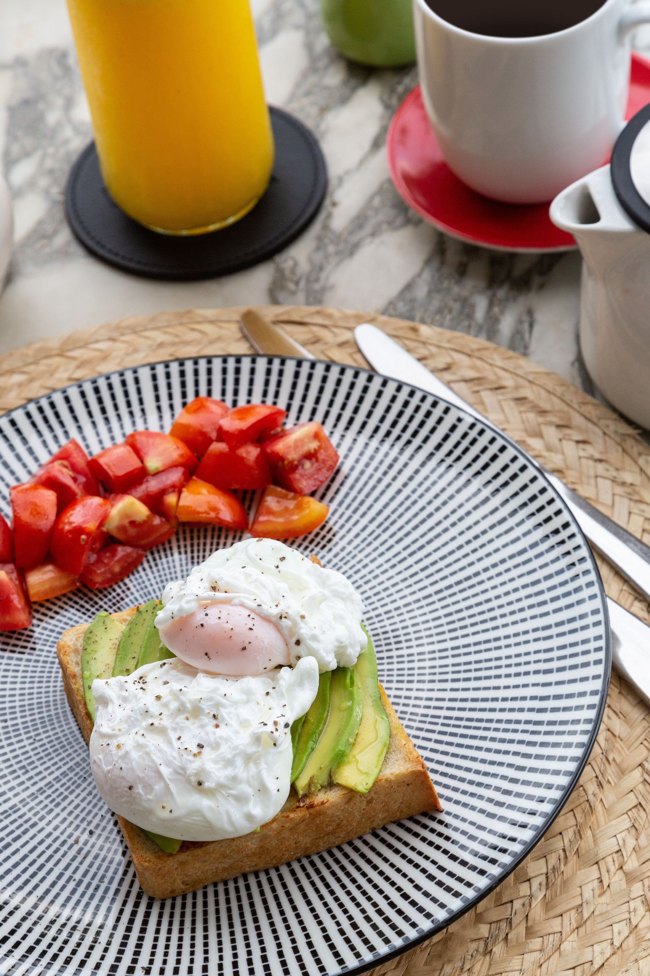 A breakfast plate with toast, avocado, a poached egg, and diced tomatoes.