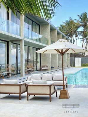 A modern outdoor lounge area with wicker furniture and a pool.