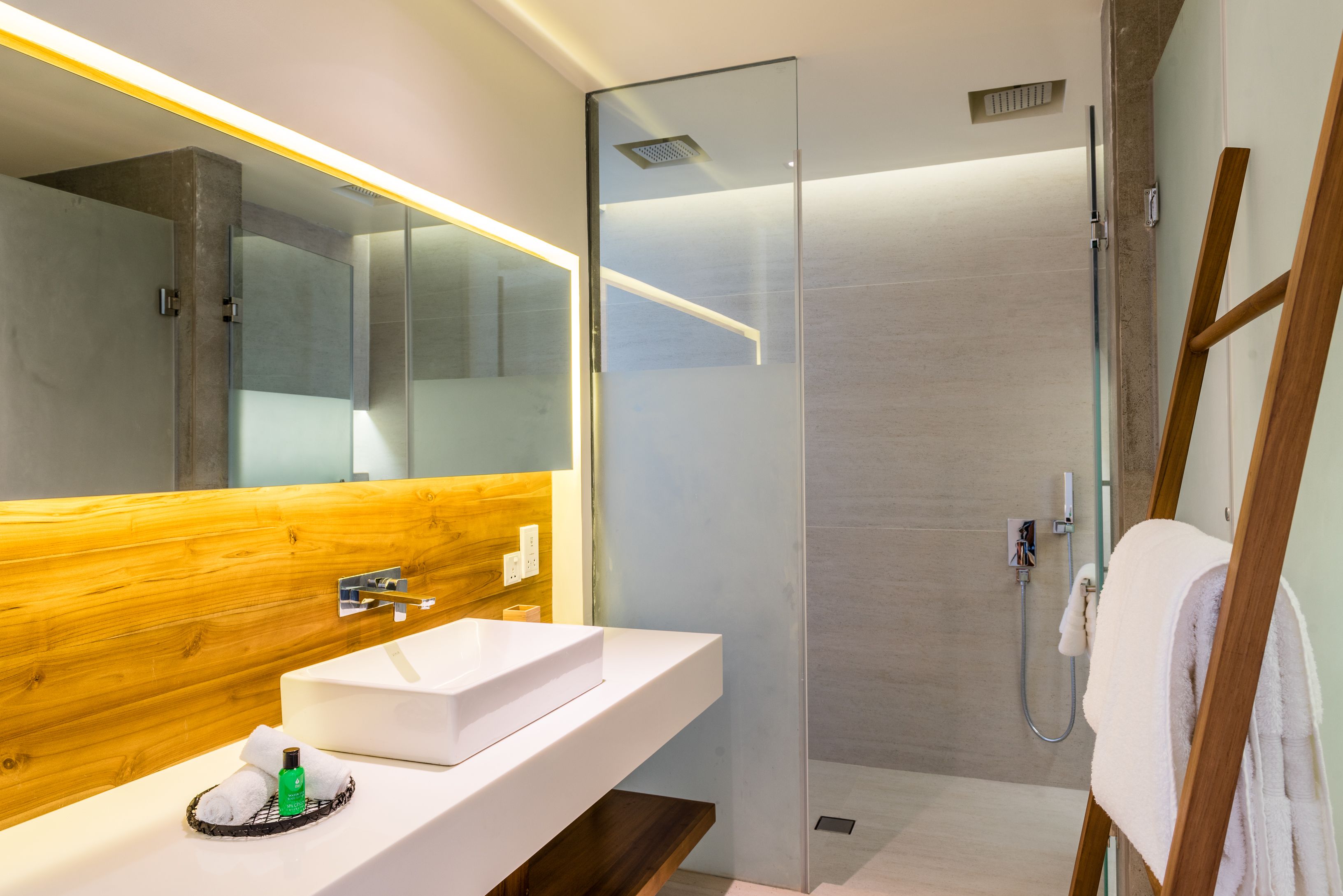 A modern bathroom with a wooden vanity, a large mirror, and a glass-enclosed shower.